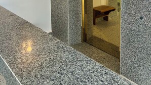A hotel lobby with granite walls, a glass door entrance, a wooden bench, and a no-smoking sign. - A Z Hotel Phnom Penh (Phnom Penh)
