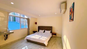 A bedroom with a bed, a window, a wall-mounted air conditioner, and a painting. - A Z Hotel Phnom Penh (Phnom Penh)