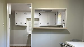 Een keuken met witte kasten, een houten vloer en een eethoek met een tafel en stoelen.