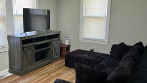 Een woonkamer met een donker houten entertainmentkast, een zwarte bank en een televisie.