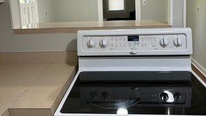 Een keuken met een wit fornuis, een magnetron en een grote spiegel boven het fornuis.