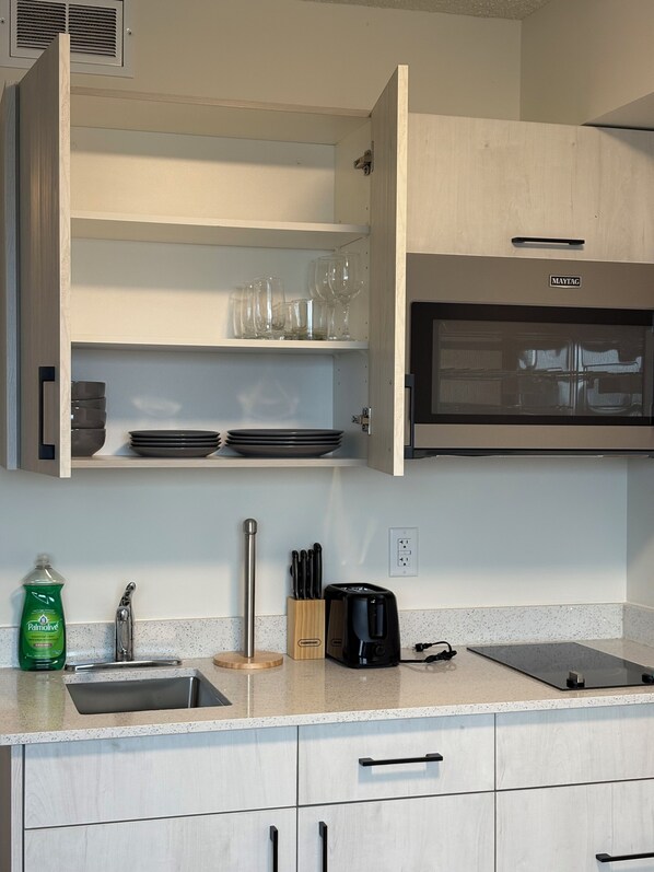 A kitchen with a built-in oven, a sink, and a countertop with a knife block and a toaster. - Smart Studio Stay | Work + Relax (Edmonton)