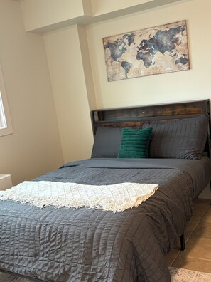 A bedroom with a bed, a headboard, a blanket, and a wall-mounted artwork. - Smart Studio Stay | Work + Relax (Edmonton)