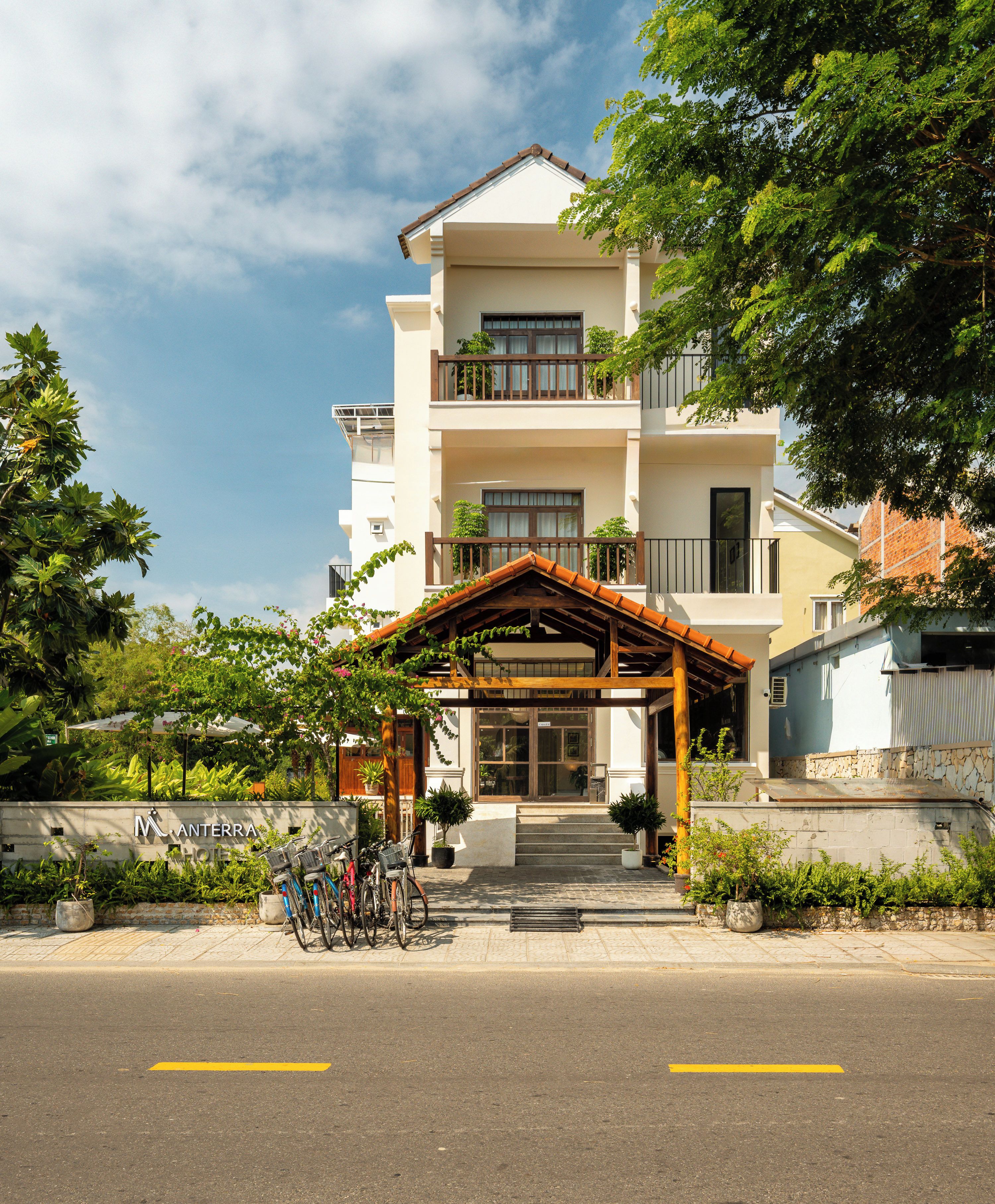 A hotel with a covered entrance, bicycles parked outside, and a clear sky.