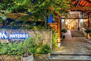 L’entrée d’un hôtel, avec un mur en pierre, des marches menant à un bâtiment et une enseigne indiquant « ANTERRA HOTEL ».