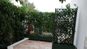 A courtyard with a tiled floor, green planters, and a lattice fence. - Villa Marisol with parking space and large garden (San Pietro In Bevagna)