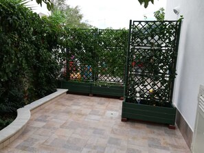 A courtyard with a tiled floor, green planters, and a lattice fence. - Villa Marisol with parking space and large garden (San Pietro In Bevagna)