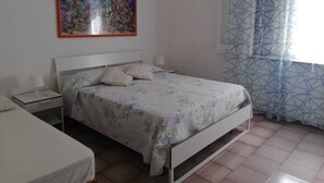 A bedroom with a bed, a nightstand, a painting, and patterned curtains. - Villa Marisol with parking space and large garden (San Pietro In Bevagna)