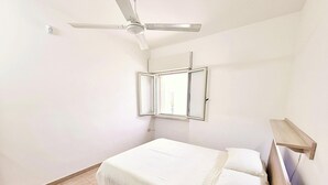 A bedroom with a bed, a ceiling fan, a window, and a wooden shelf. - Villa with sea view in San Gregorio - Patu (Patu')