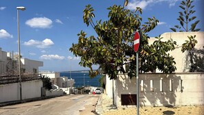 A street with a stop sign, a tree, and a building with a view of the sea. - Villa with sea view in San Gregorio - Patu (Patu')