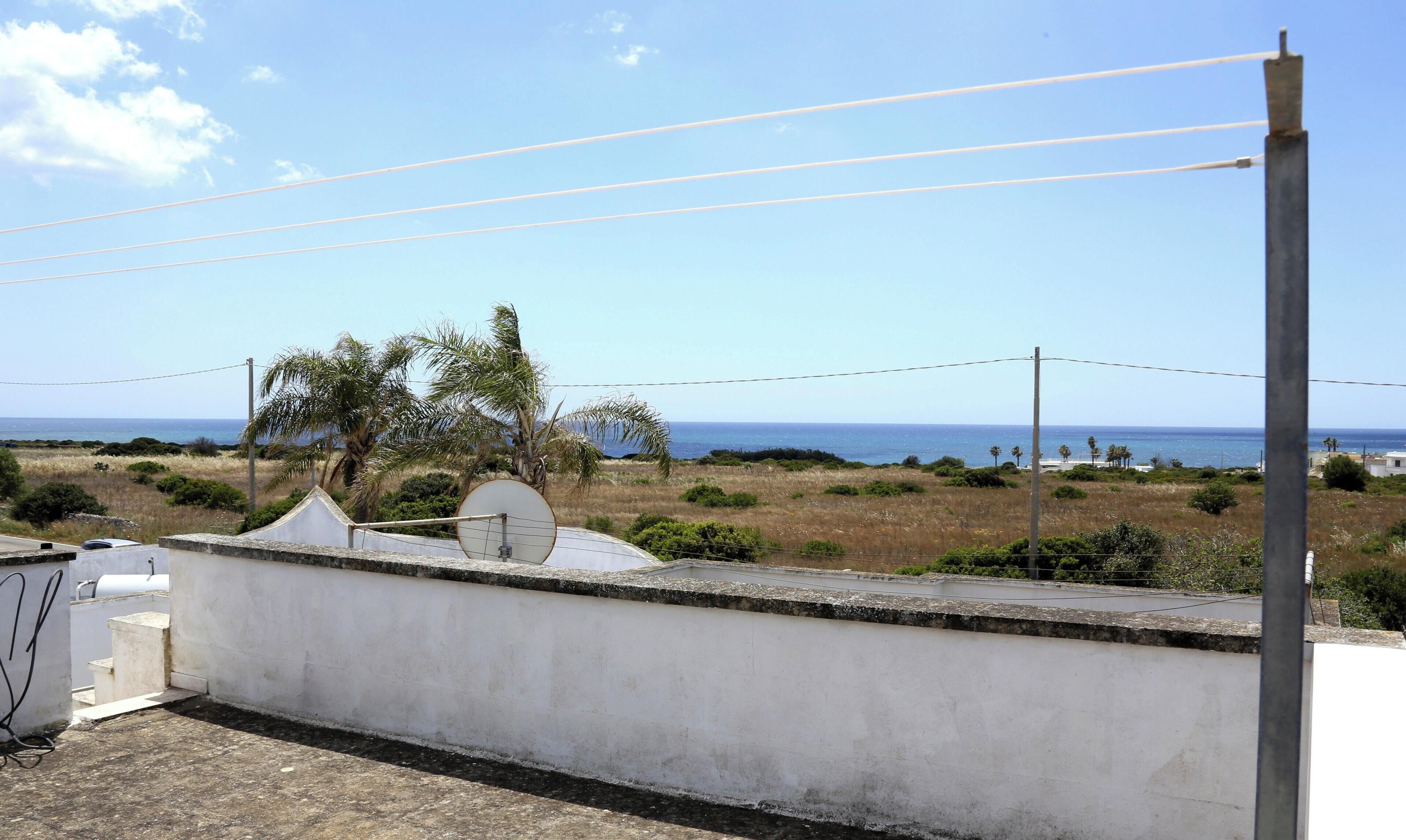 Eine Dachterrasse mit Blick aufs Meer, einer Satellitenschüssel und einer weißen Wand.