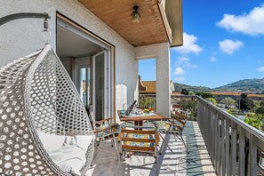 Een balkon met rieten meubels, een tafel en stoelen, met uitzicht op een prachtig landschap.
