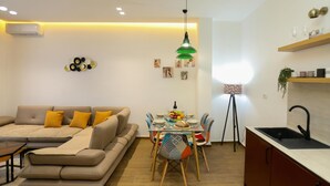 Una sala de estar moderna con sofá, mesa de comedor y zona de cocina.