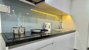 A modern kitchen with a black countertop, stainless steel appliances, and a white backsplash. - Nghe Home (Da Nang)