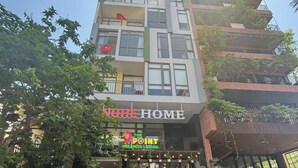 A multi-story building with a wellness lounge on the ground floor, outdoor seating, and a staircase leading to the entrance. - Nghe Home (Da Nang)