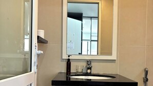 A bathroom with a white sink, a mirror, and a shower. - Nghe Home (Da Nang)