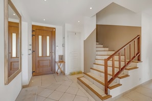 Een trap met houten leuningen en vloertegels in beige tint.