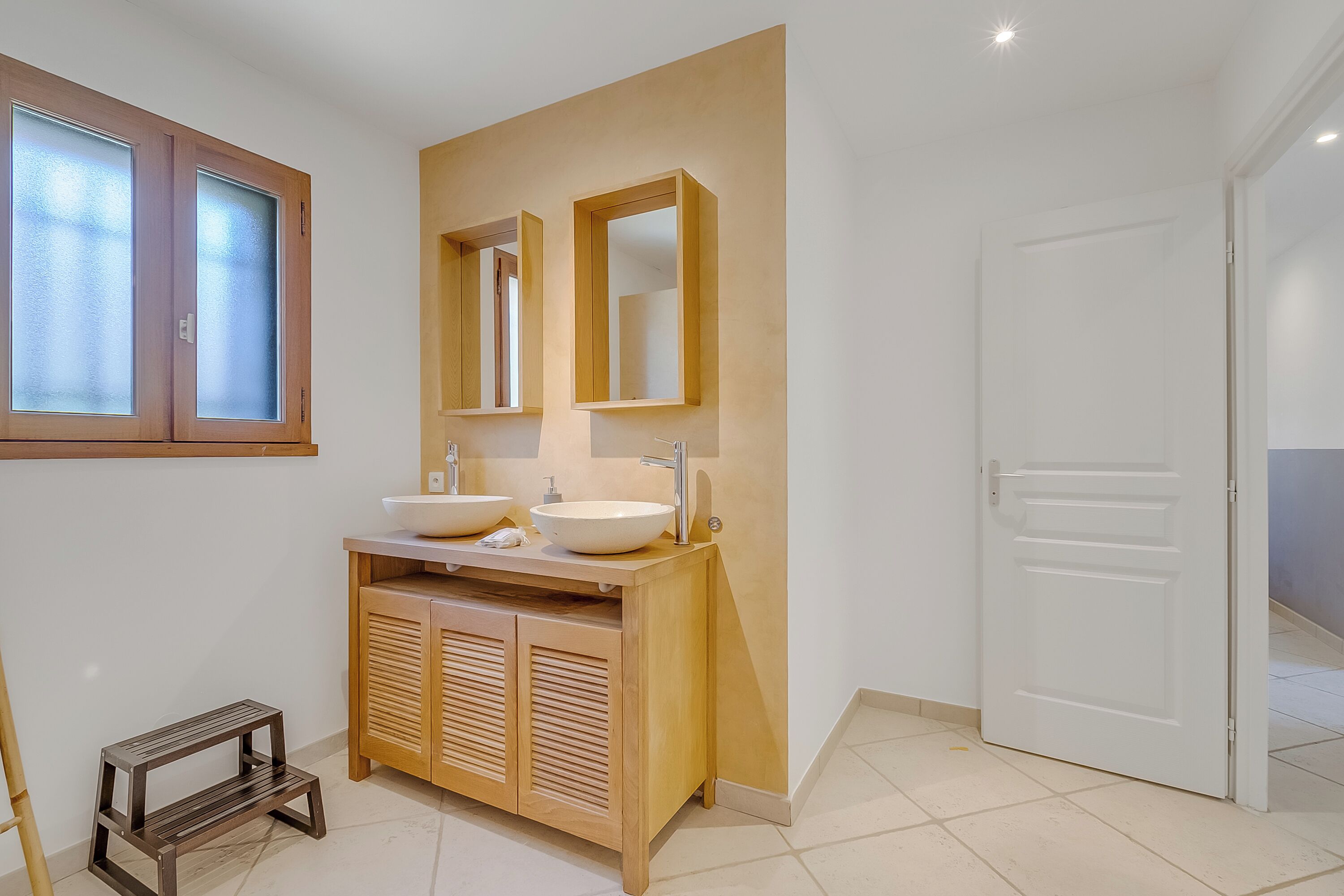 A bathroom with two sinks, a wooden vanity, and a door.