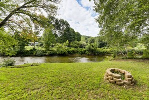 Une zone herbeuse avec une rivière, des arbres et une structure en pierre.