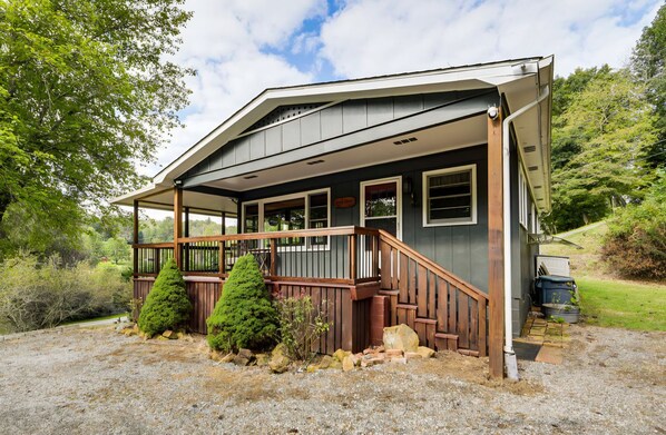 A two-story building with a covered porch, wooden railings, and a gravel driveway.