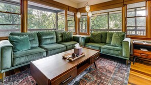 Una habitación con dos sofás verdes, una mesa de centro de madera y un escritorio con una silla.