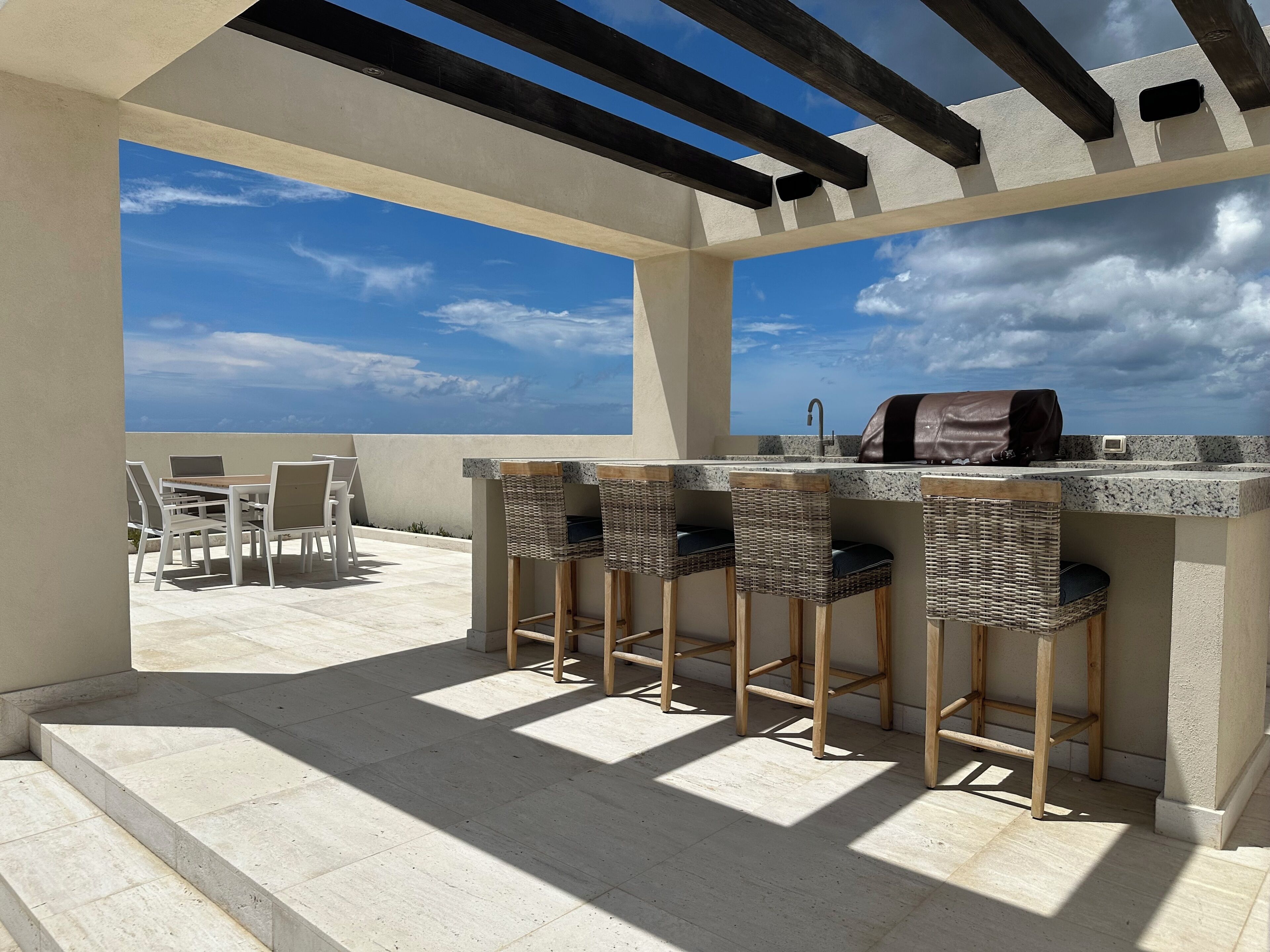 An outdoor bar area with a view of the sky, a grill, and seating.