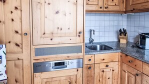 A kitchen with wooden cabinets, a Bosch dishwasher, a sink, and a knife block. - Chesa Piz Alv - Roseg Spirit by Interhome (Pontresina)