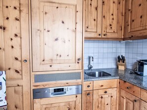 A kitchen with wooden cabinets, a Bosch dishwasher, a sink, and a knife block. - Chesa Piz Alv - Roseg Spirit by Interhome (Pontresina)