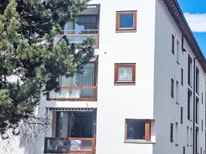 A multi-story building with several windows, a balcony, and a tree in the foreground. - Chesa Piz Alv by Interhome (Pontresina)