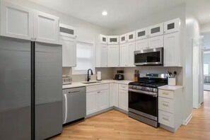 Une cuisine moderne avec des meubles blancs, des appareils en acier inoxydable et un plancher en bois.