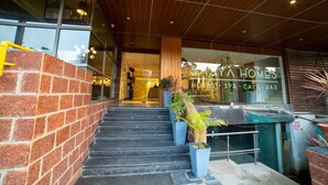 A hotel entrance with a brick wall, a staircase leading to the entrance, and a sign for 'SAY A HOMES HOTEL SPA CAFE BAR'. - The Elite Royale (Bengaluru)