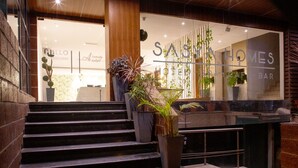 A hotel entrance with a staircase leading to a reception area, a bar, and a visible sign for 'SASYA HOTEL SPA BAR'. - The Elite Royale (Bengaluru)