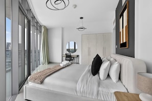 A modern bedroom with a large bed, a desk, a mirror, and a view of the city. - Silkhaus Premium 2bdr in Julphar Near Reem Park (Abu Dhabi)