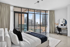 A modern hotel room with a large bed, a desk, and a view of a cityscape through floor-to-ceiling windows. - Silkhaus Modern 2bdr Flat in Julphar Tower (Abu Dhabi)
