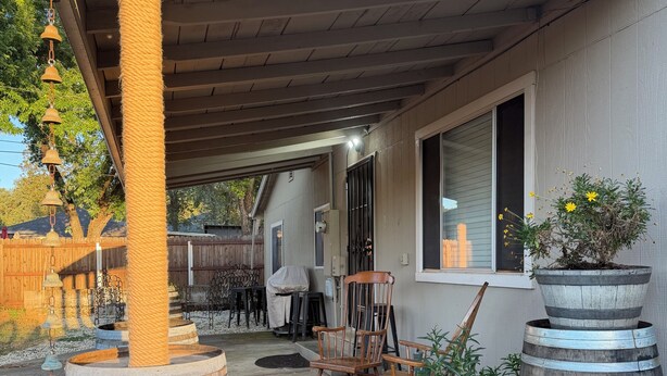 Un patio couvert agrémenté de barils en bois, d’un arbre à chat et de mobilier d’extérieur.