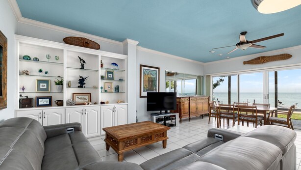 A living room with a sofa, TV, wooden coffee table, and a view of the ocean. - Ground floor Madre walk out w/boat slip! (South Padre Island)