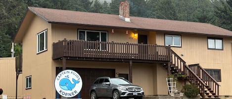 A two-story building with a wooden deck and a car parked in front.