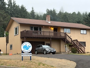 A two-story building with a wooden deck and a car parked in front. - Captain Kujo’s Hideaway (Depoe Bay)