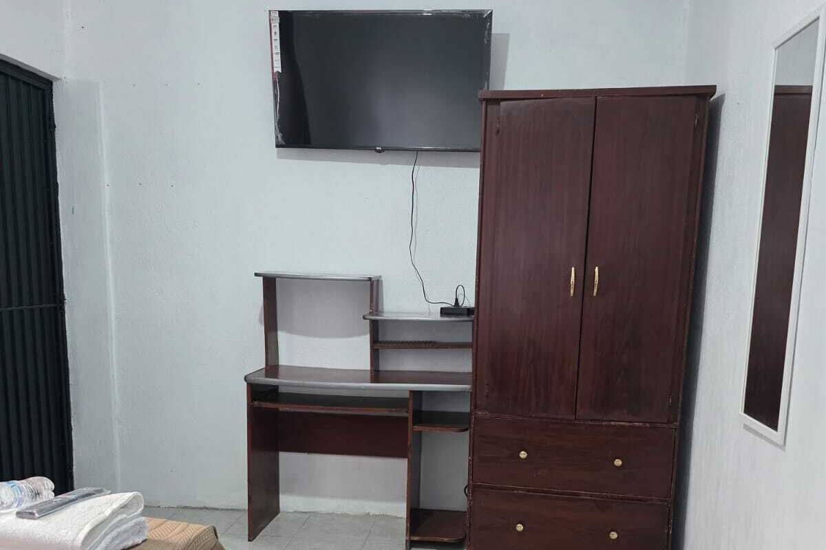 Ein Schlafzimmer mit Bett, Schreibtisch, Kleiderschrank und einem Fernseher an der Wand.