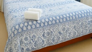 A neatly made bed with a patterned bedspread, a wooden headboard, and a nightstand with a vase of flowers. - Friendly Homestay - Ormiston, Auckland (Auckland)