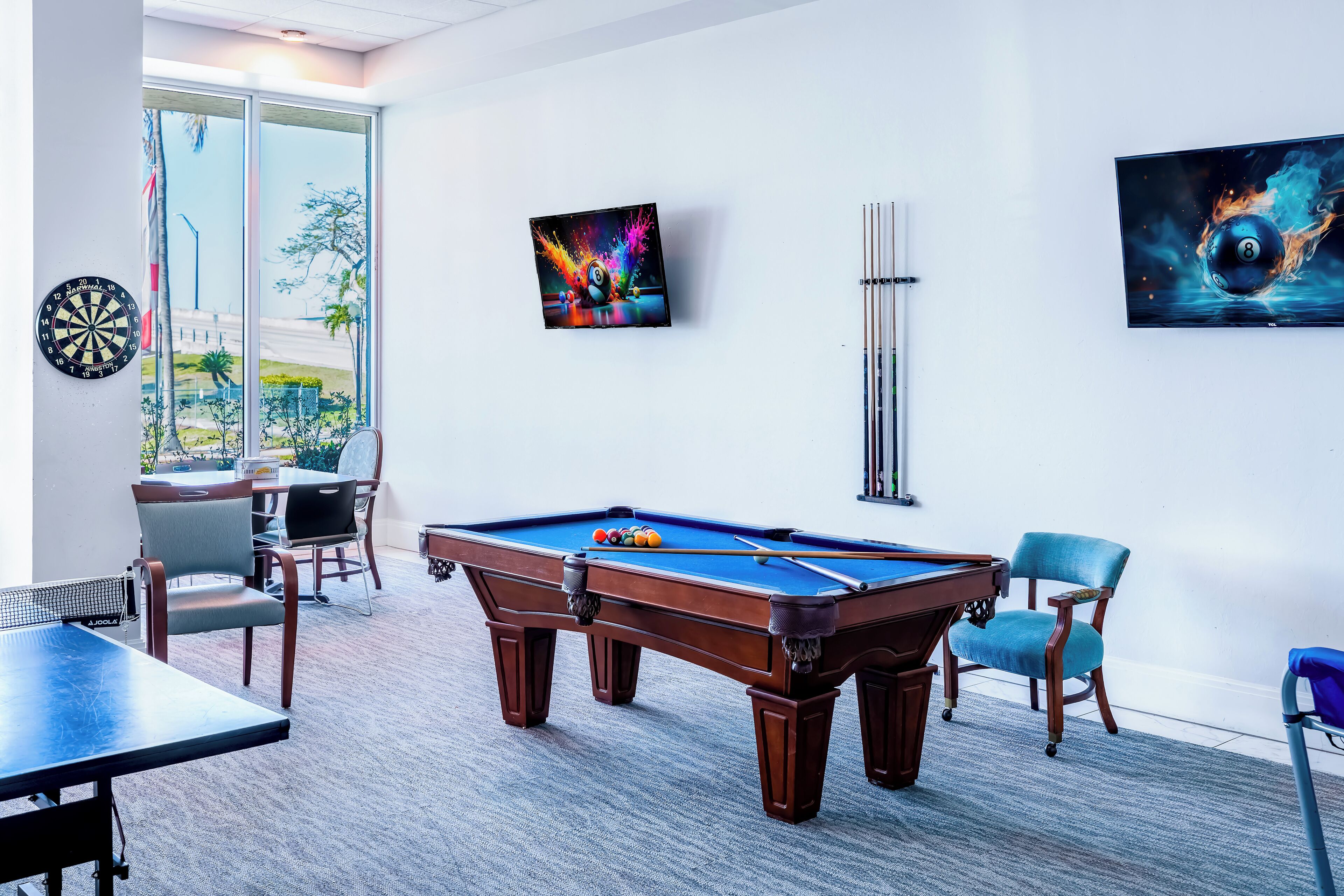 Une table de billard avec un jeu de fléchettes, une table de snooker et un téléviseur fixé au mur.