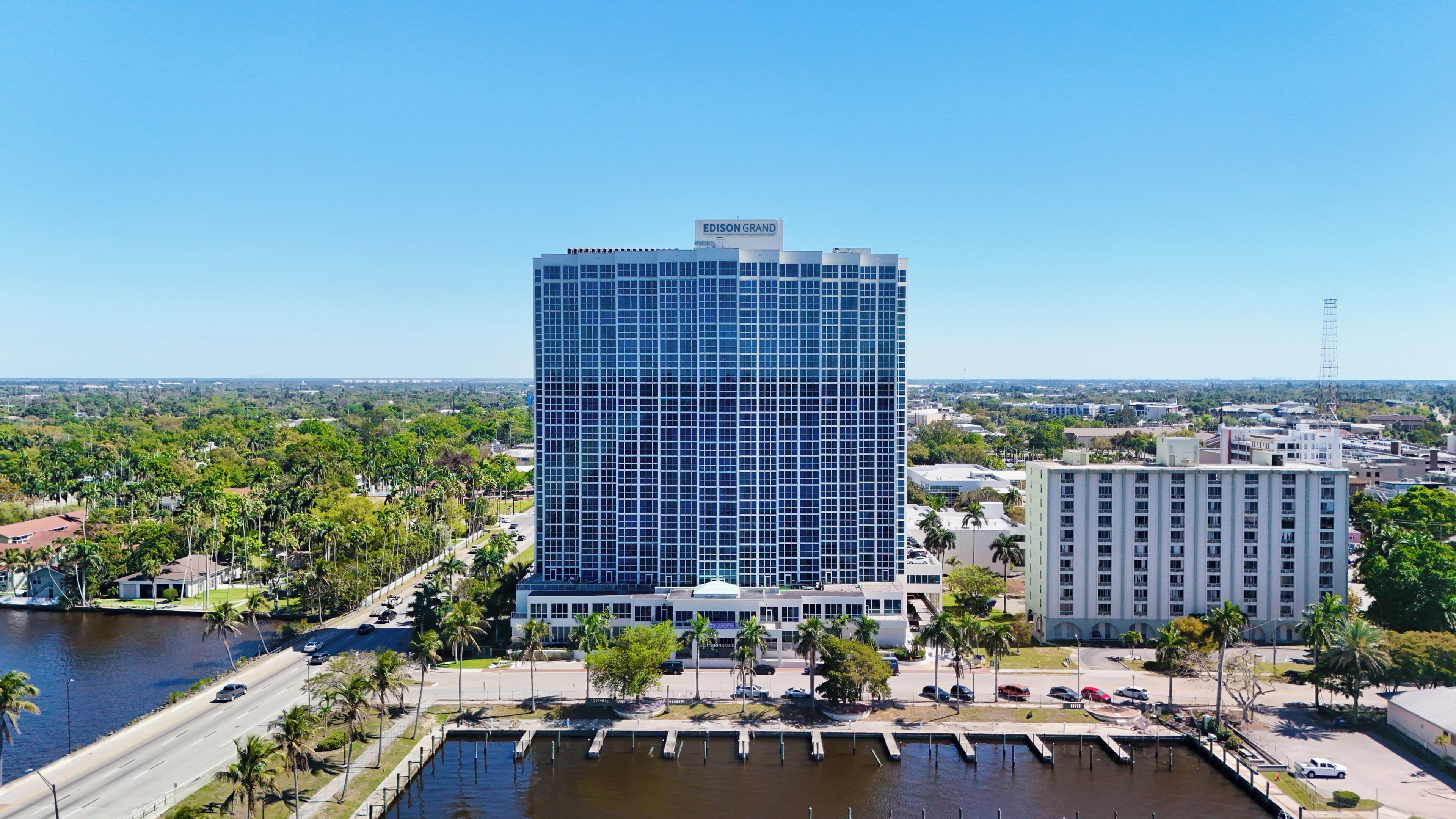 A high-rise building with a grid-like facade, a marina with docks, and a clear view of the surrounding urban landscape.