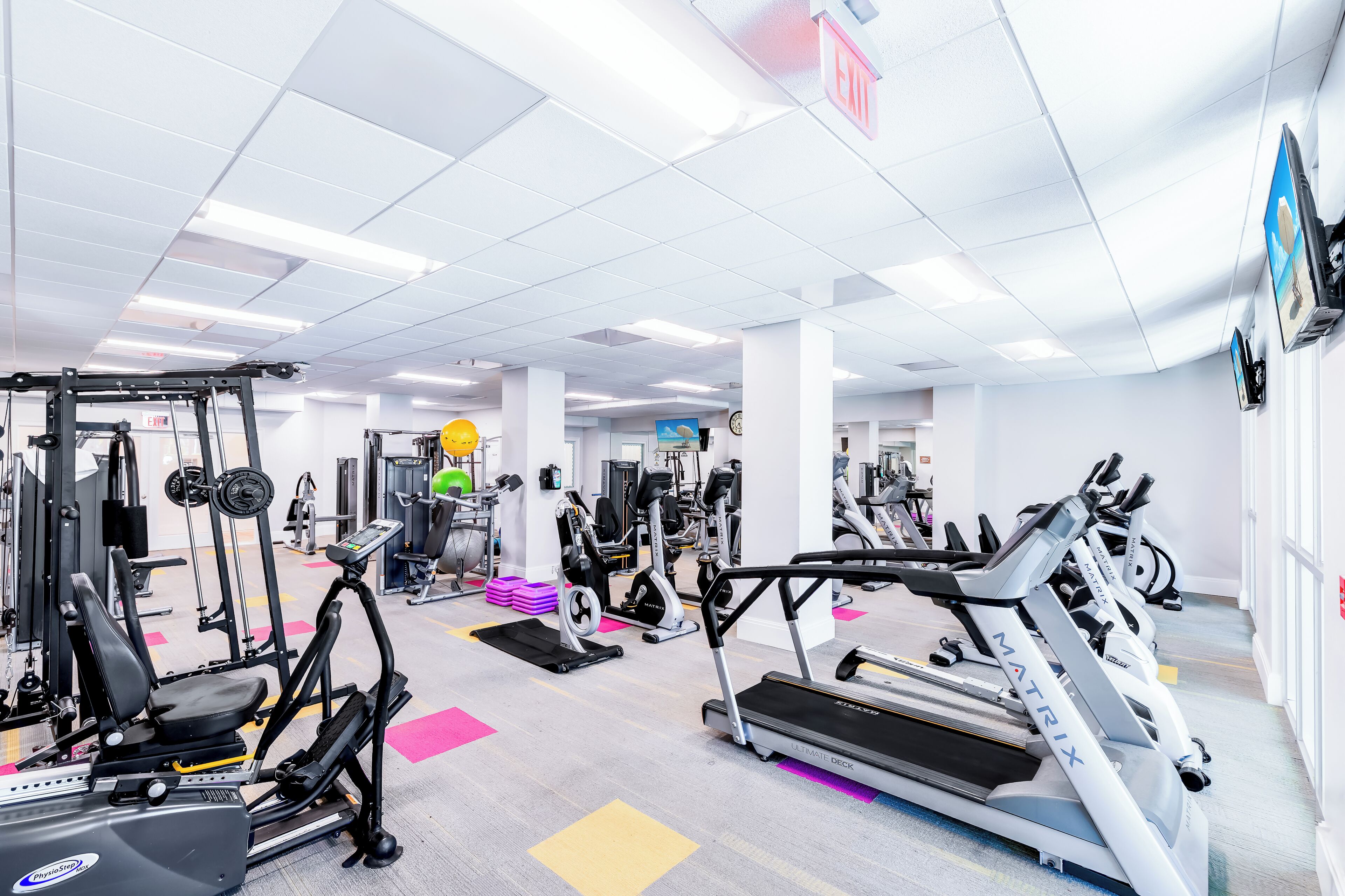 Un gimnasio con cintas de correr, elípticas y máquinas de pesas.