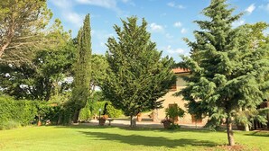 Un giardino con diversi alberi e un edificio con tetto rosso.