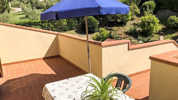 Un balcón con una mesa, una silla y una planta en maceta.
