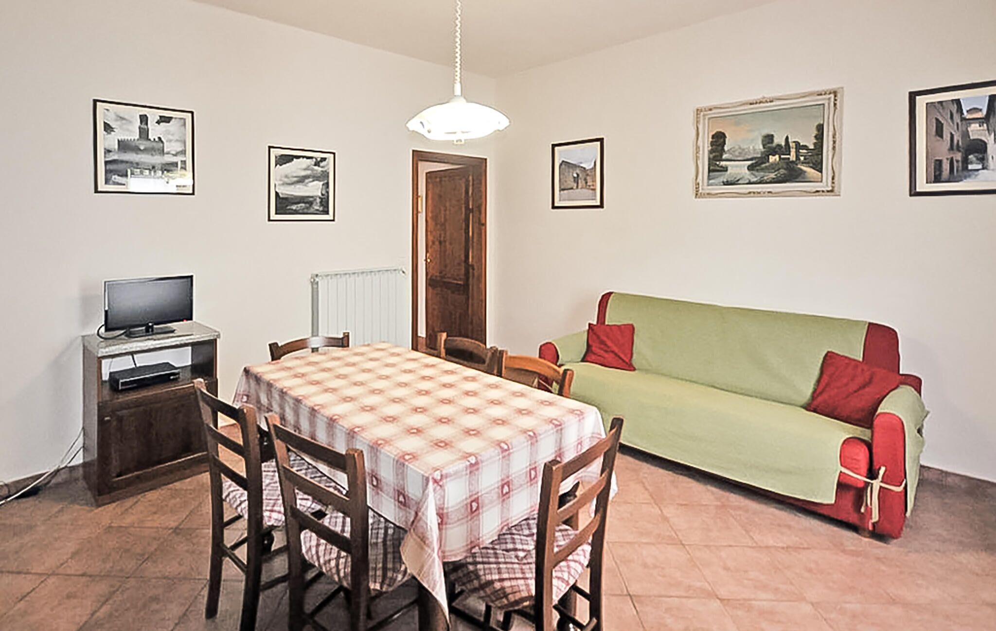 A dining area with a table, chairs, a television, and a sofa.