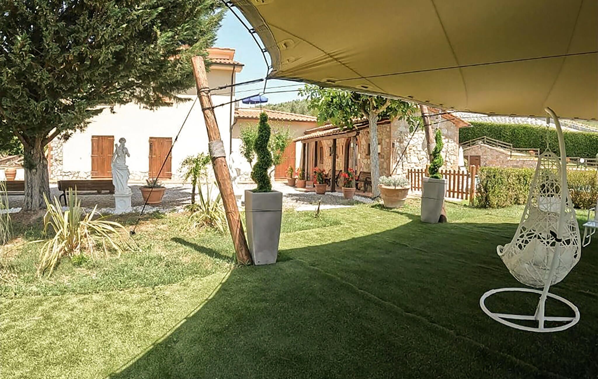 Un espace patio aménagé avec une tente, des plantes en pot et une statue.