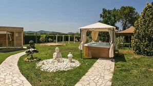 A garden with a hot tub, a Buddha statue, and a gazebo. - Stunning apartment in Montecatini Val di Cecina (Montecatini Val di Cecina)