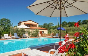 A pool area with lounge chairs and umbrellas, a building with a tiled roof, and a clear blue sky. - Stunning apartment in Montecatini Val di Cecina (Montecatini Val di Cecina)
