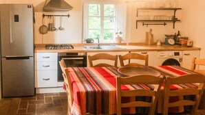 Une cuisine équipée d’un réfrigérateur, d’une cuisinière, d’un four et d’une table à manger en bois avec des chaises.